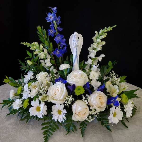White and blue floral arrangement with a central angel figurine