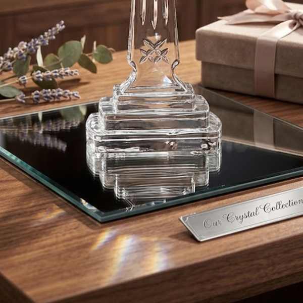 Clear glass cross on a wooden table beside a gift box