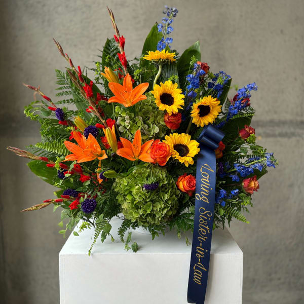 Colorful bouquet with sunflowers, orange lilies, and blue flowers in a vase