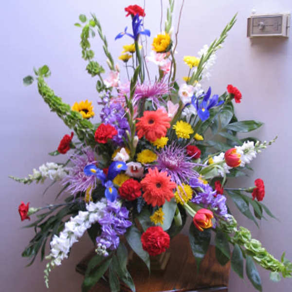 Tall mixed flower arrangement with bright red, yellow, blue, and purple blooms