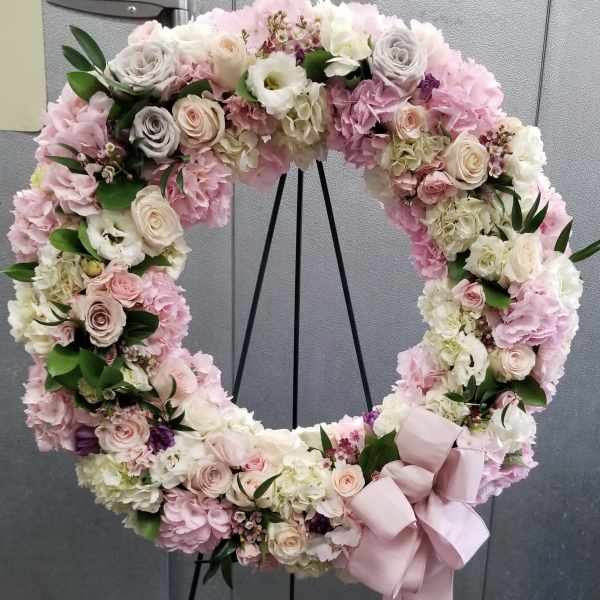 Pastel floral wreath with roses, hydrangeas, and a pink ribbon bow