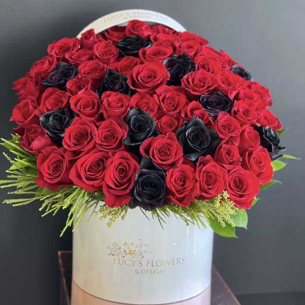 Round bouquet of red and black roses in a white hat box