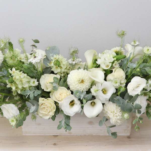 Long white floral arrangement in a low rectangular container