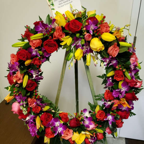 Colorful floral wreath on a stand with a sympathy card