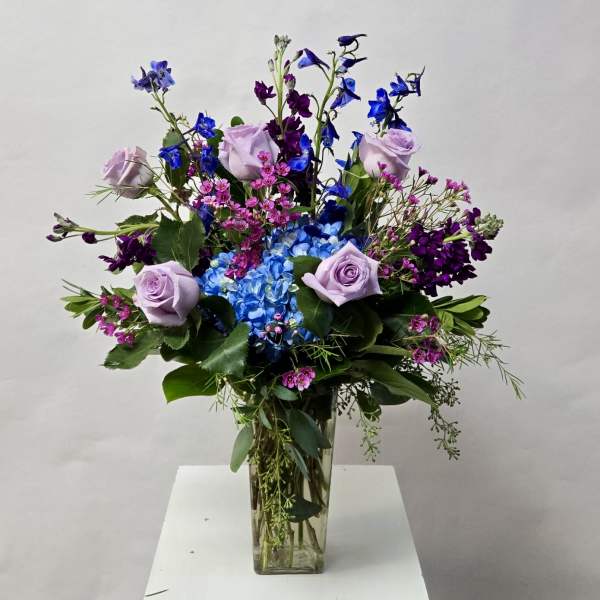 Lavender roses and blue hydrangea in a clear glass vase