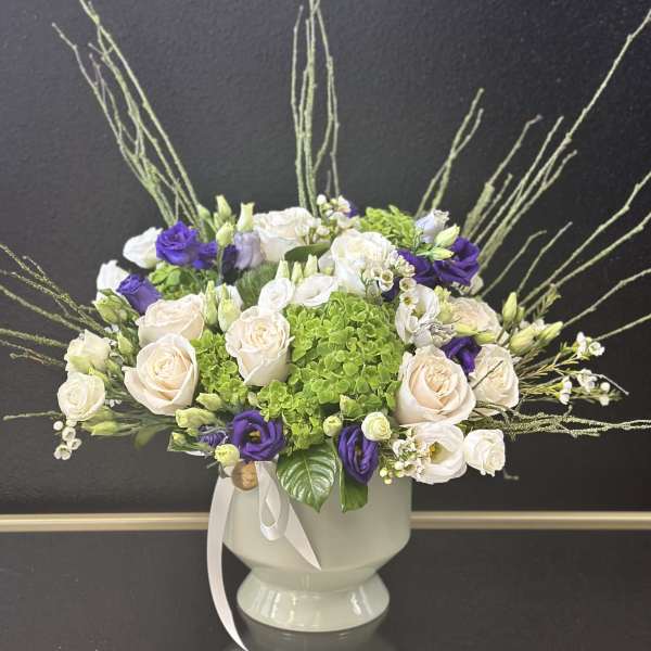 Bouquet of cream and purple roses in a white vase
