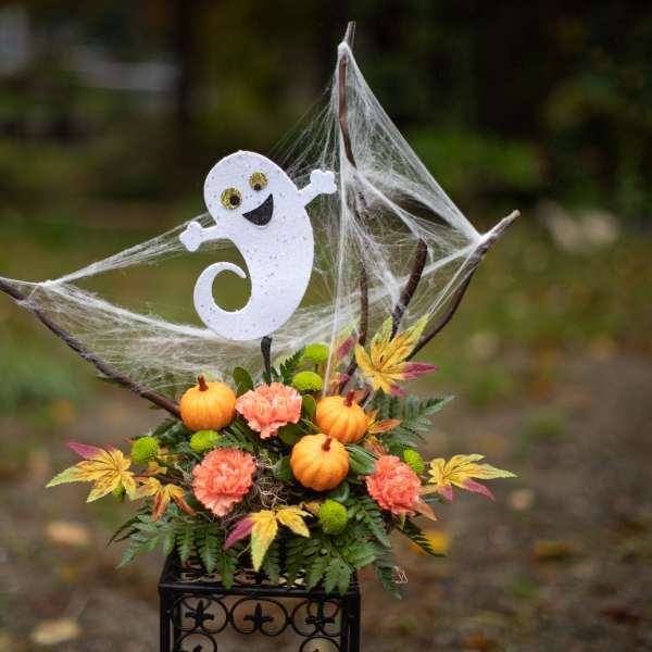 Halloween floral arrangement with pumpkins and a ghost topper