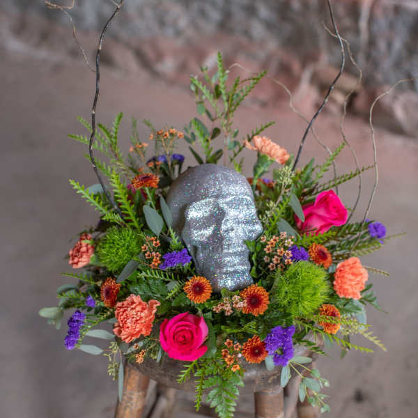 Floral arrangement with a glittery skull centerpiece on a stool