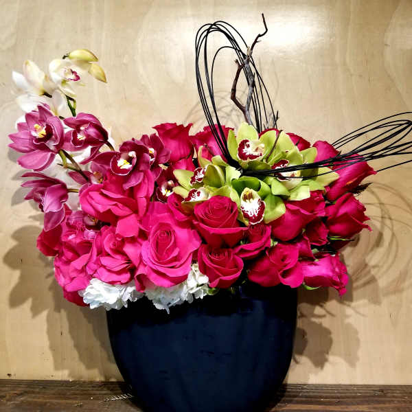 Pink roses and orchids arranged in a dark vase