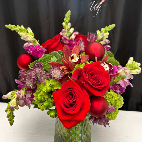 Red roses and purple flowers in a glass vase with red ornaments
