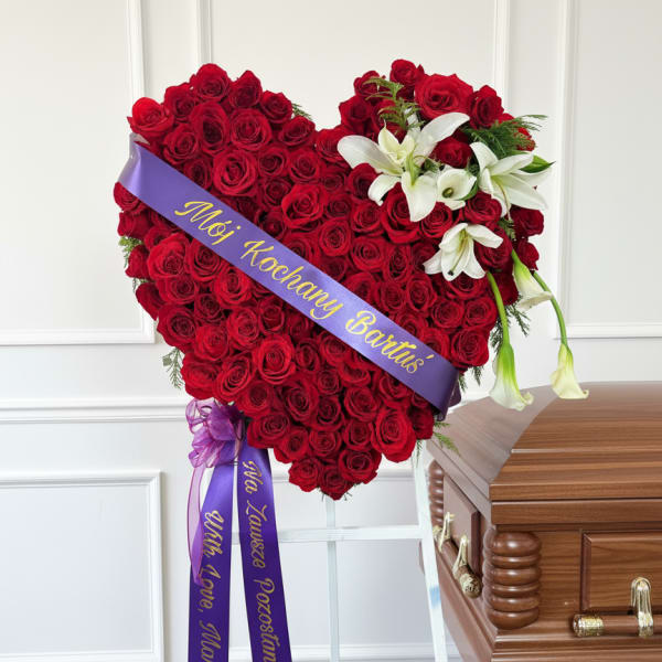 Heart-shaped red rose funeral spray with white lilies and purple ribbons