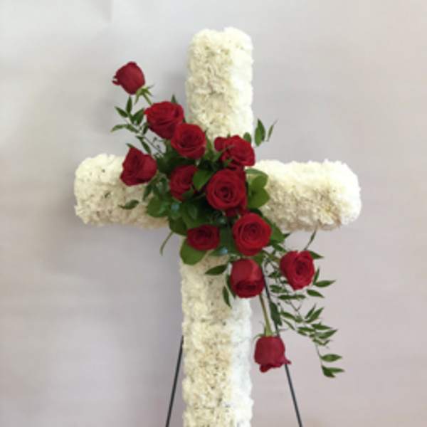White floral cross with red roses on a stand