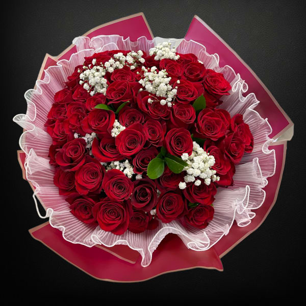 Bouquet of red roses with white baby's breath in pink wrapping