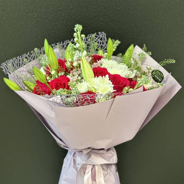 Bouquet of red roses and white lilies wrapped in pale paper