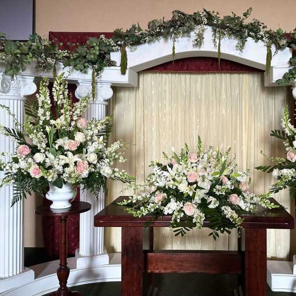 Wedding altar with white and blush floral arrangements on columns and table