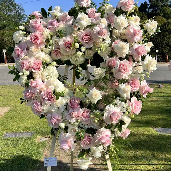 Large heart-shaped floral wreath of pink and white roses on an easel