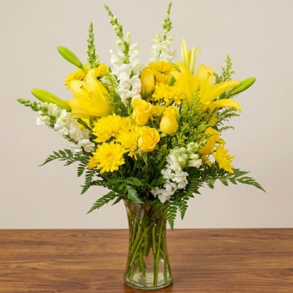 Yellow lilies and white snapdragons in a clear glass vase