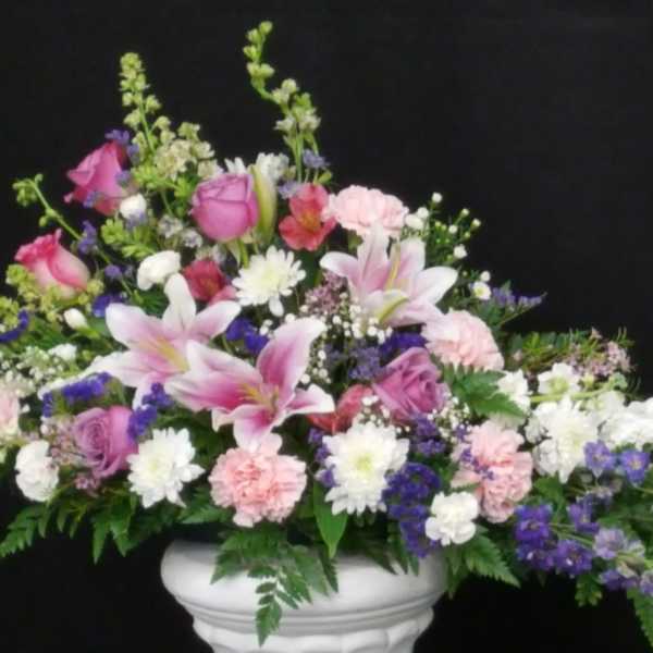 Pink and white mixed flower arrangement in a white pedestal vase