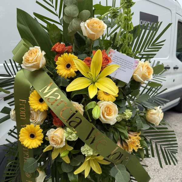 Large standing floral spray with yellow lilies, roses, and gerbera daisies