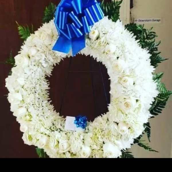White floral funeral wreath with a blue bow