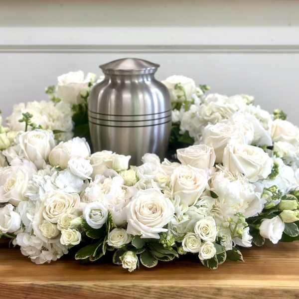 White rose and hydrangea funeral wreath around a silver urn
