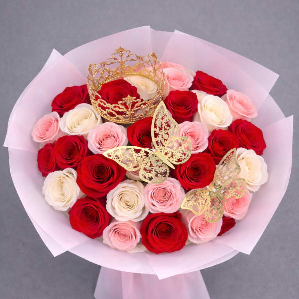 Bouquet of red, pink, and white roses with gold crown and butterfly accents