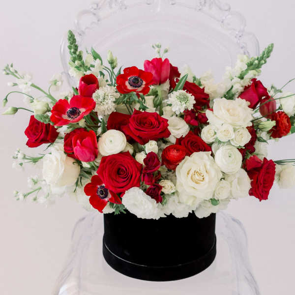 Red and white rose bouquet in a black hat box
