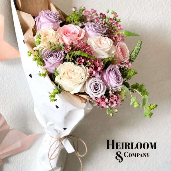Bouquet of pastel roses wrapped in white paper with a twine tie