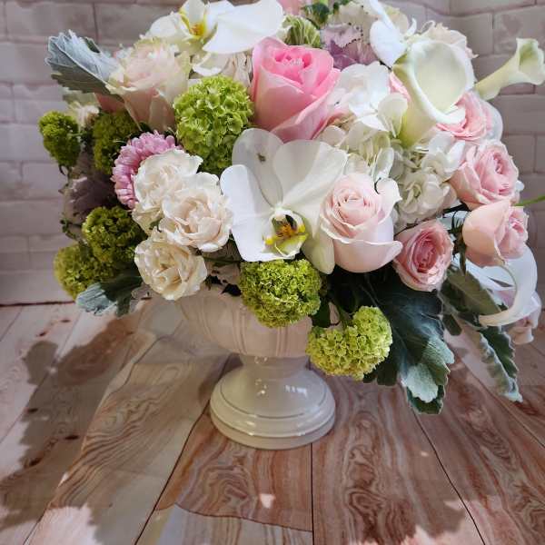 Pink and white floral arrangement in a white pedestal vase
