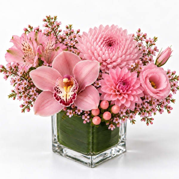 Pink floral arrangement in a clear square vase