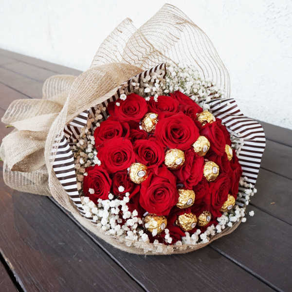 Bouquet of red roses with gold-wrapped chocolates and baby’s breath