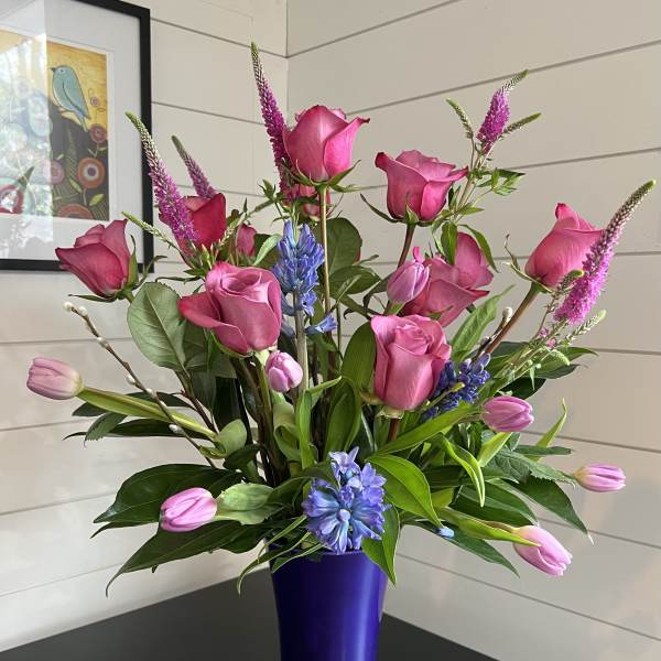 Pink roses and tulips in a purple vase with blue accents