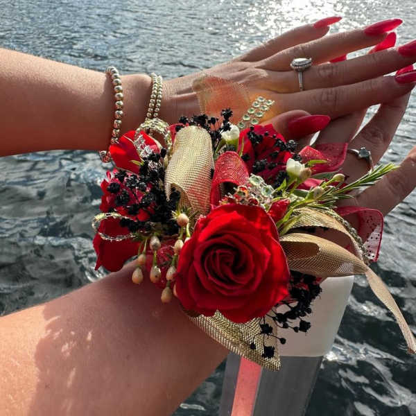 Red rose wrist corsage with gold ribbon and black accents
