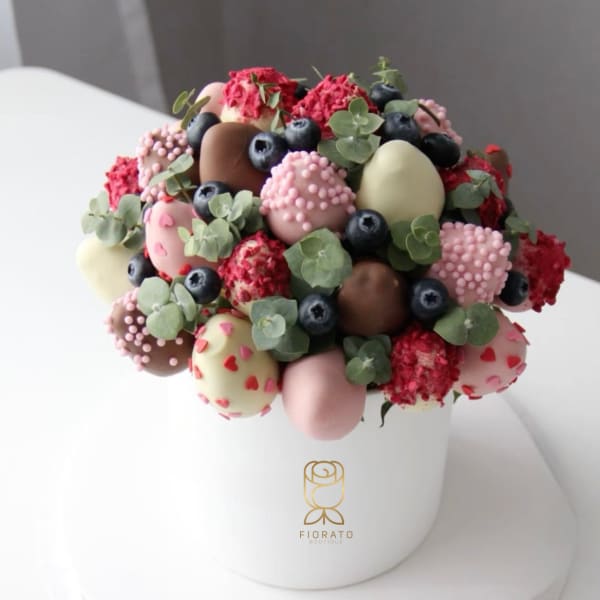 Chocolate-covered strawberries and blueberries in a white hatbox