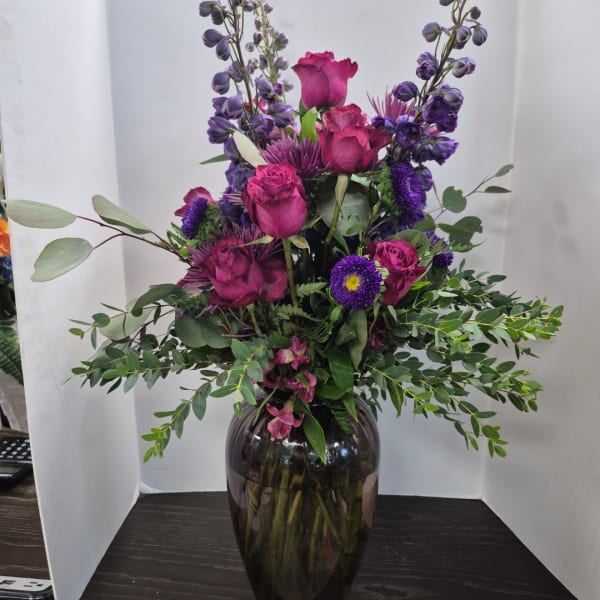 Purple and pink floral arrangement in a dark glass vase