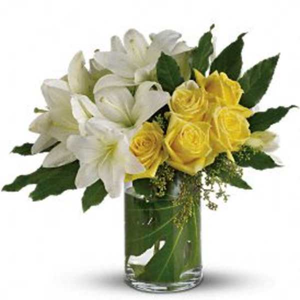White lilies and yellow roses in a clear glass vase