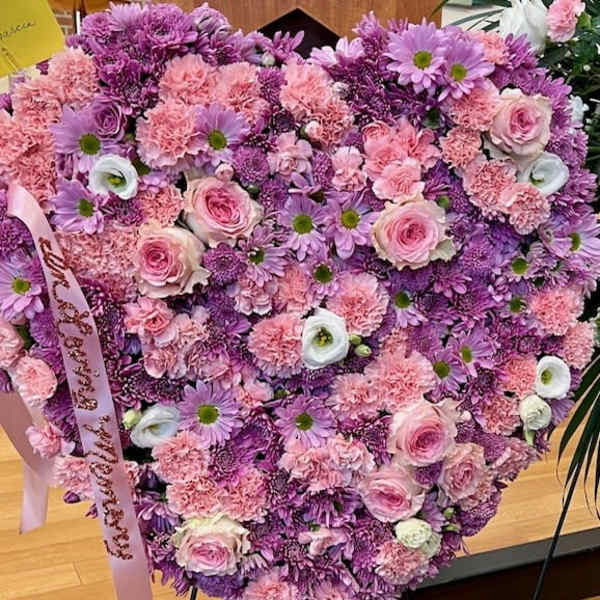 Heart-shaped bouquet of pink and purple flowers with a ribbon