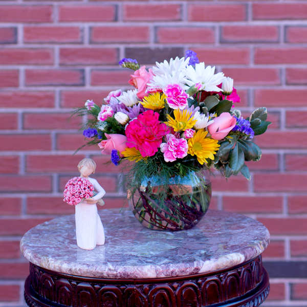 Colorful bouquet in a glass vase beside a small figurine