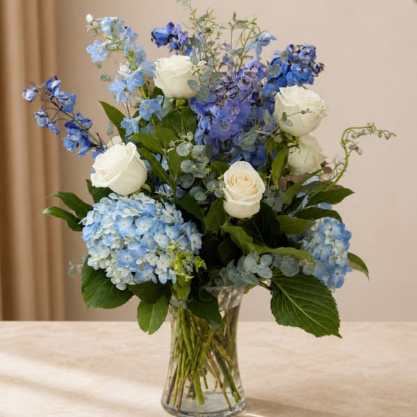 Blue and white flower arrangement in a clear glass vase