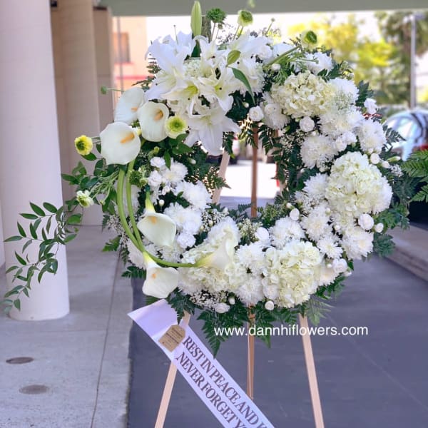 White funeral wreath on a wooden easel with a memorial ribbon