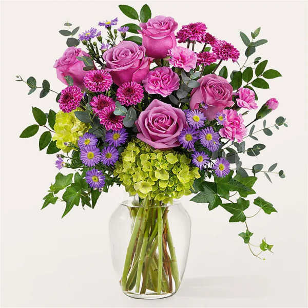 Pink roses and purple flowers in a clear glass vase