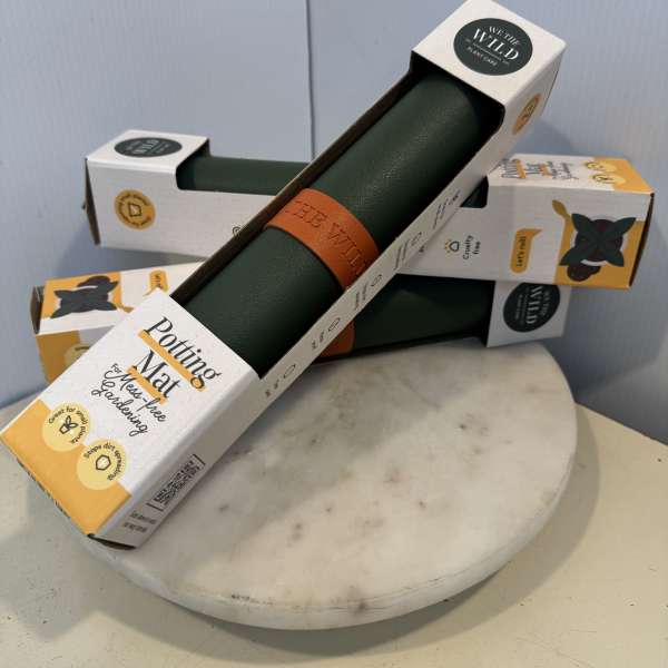 Stacked plant care mats in retail packaging on a round marble stand