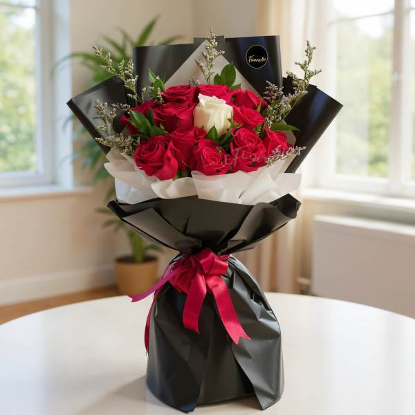 Bouquet of red and white roses wrapped in black paper with a pink ribbon