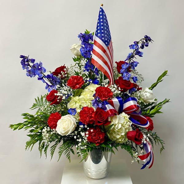 Red, white, and blue floral arrangement with an American flag in a vase