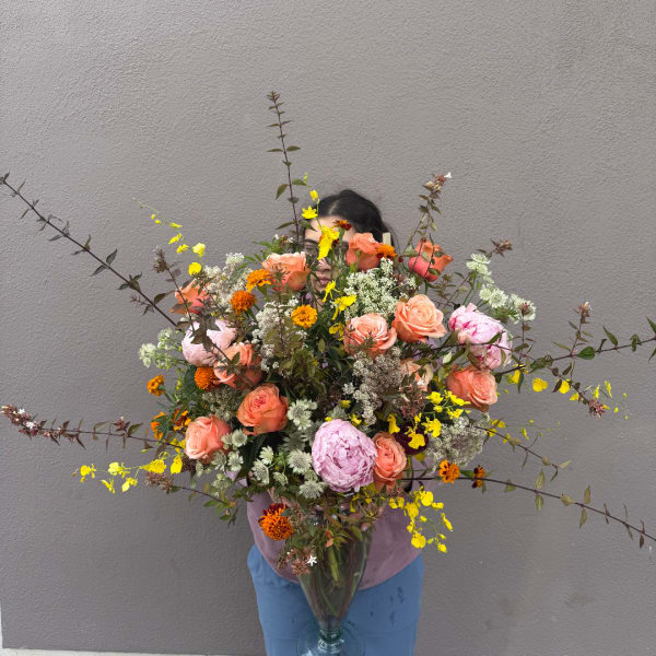Large mixed bouquet with peach and pink roses in a clear vase