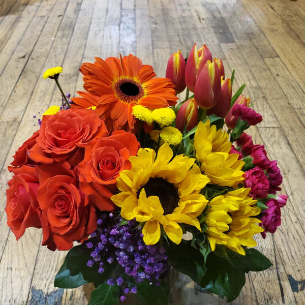 Bouquet of red roses, orange gerbera daisies, yellow sunflowers, and pink tulips