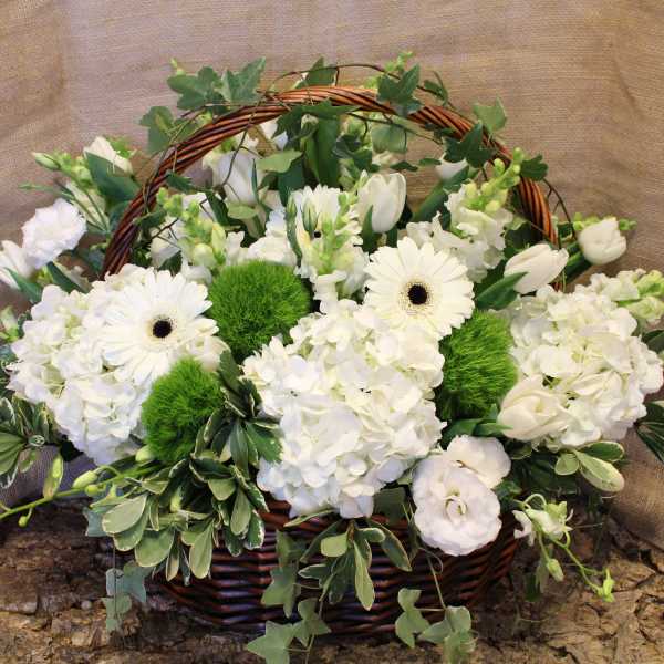 White flowers arranged in a wicker basket with green accents