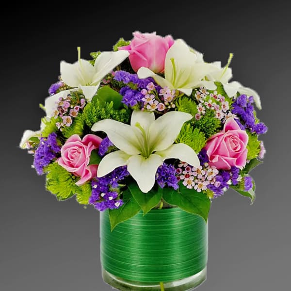 Pink roses and white lilies in a green glass vase