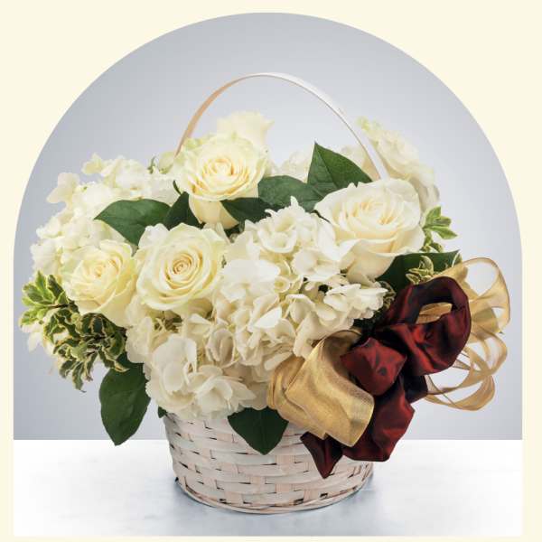 Cream roses and white hydrangeas in a woven basket with a ribbon bow