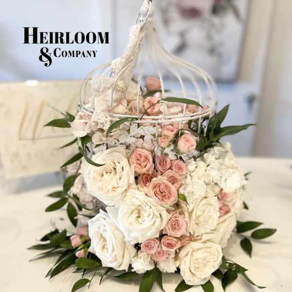 Pink and white roses arranged in a white birdcage